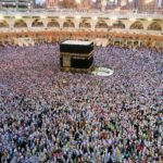 Aerial view of a large crowd of pilgrims gathered around the Kaaba in Mecca for religious rituals.